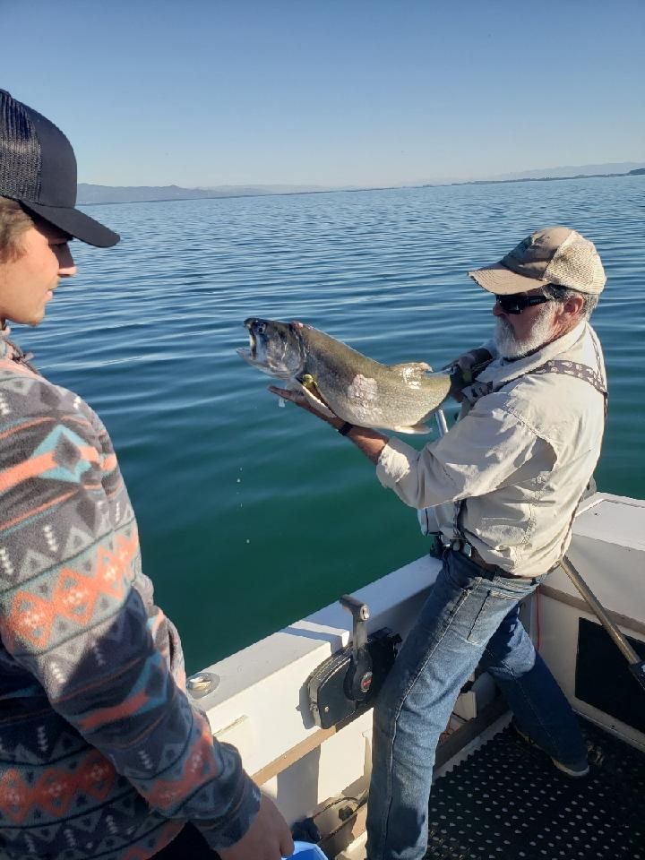 Two men are standing on a boat holding a fish.