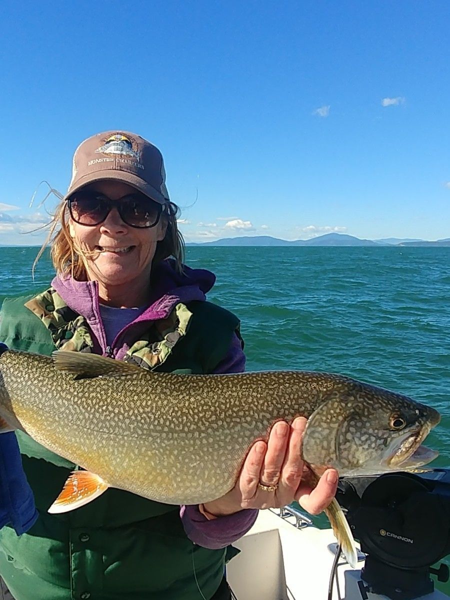 A woman is holding a large fish in her hands on a boat.