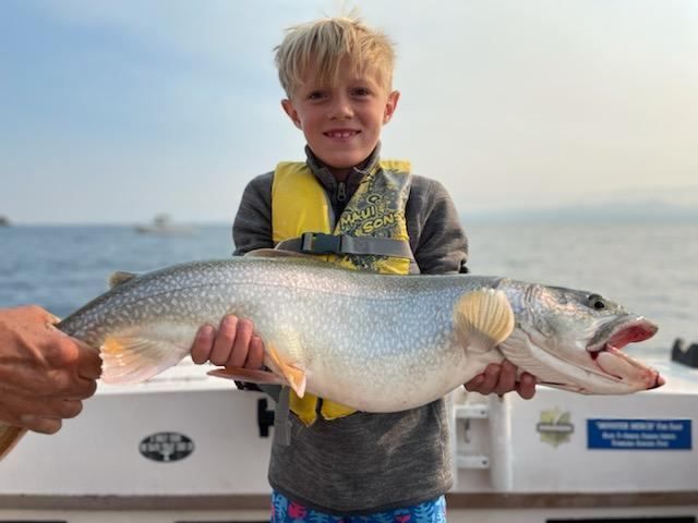 A young boy is holding a large fish on a boat.