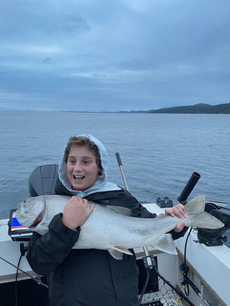 A young boy is holding a large fish on a boat.