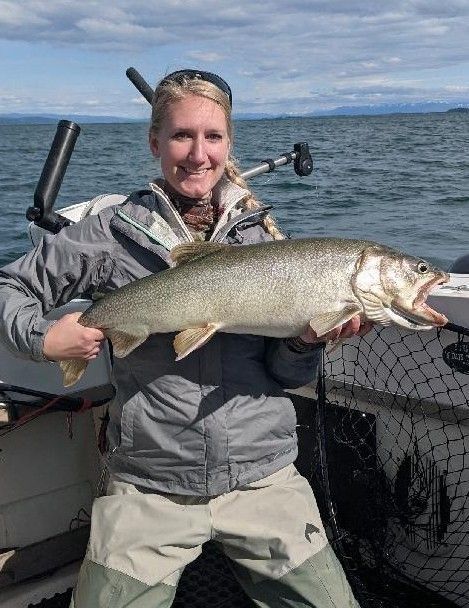 A woman is holding a large fish on a boat.