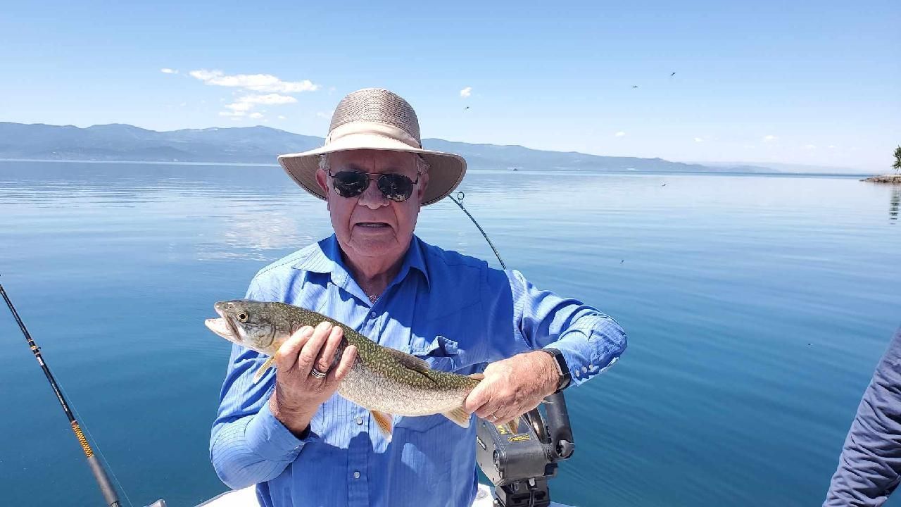 A man is holding a fish on a boat in the water.
