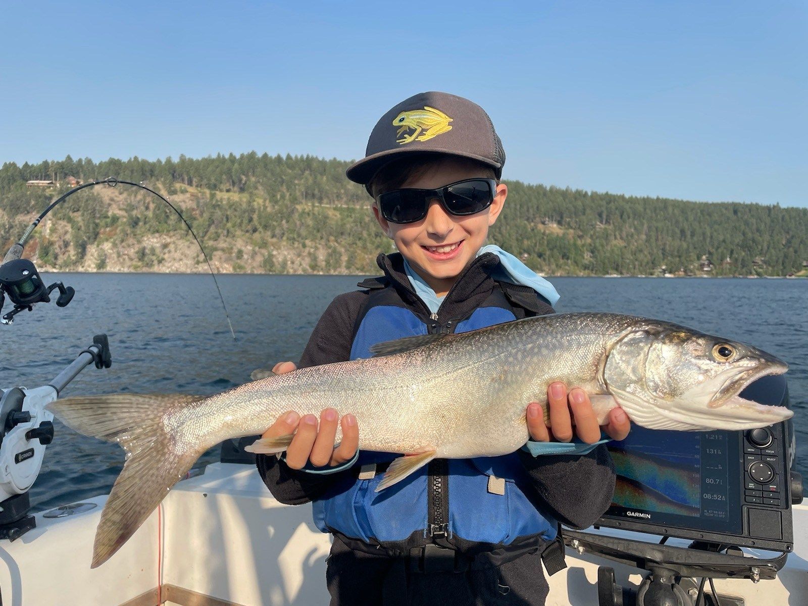 A young boy is holding a large fish on a boat.