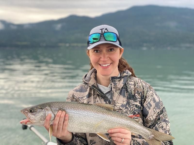 A woman is holding a large fish in her hands.