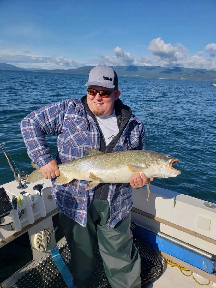 A man is holding a large fish on a boat in the water.
