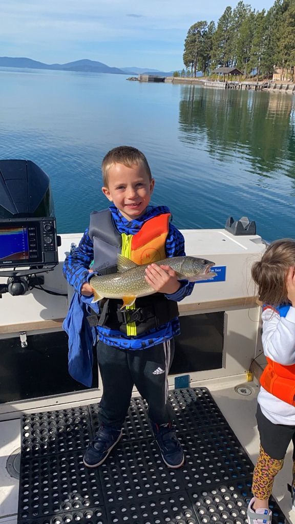 A young boy is holding a fish on a boat.
