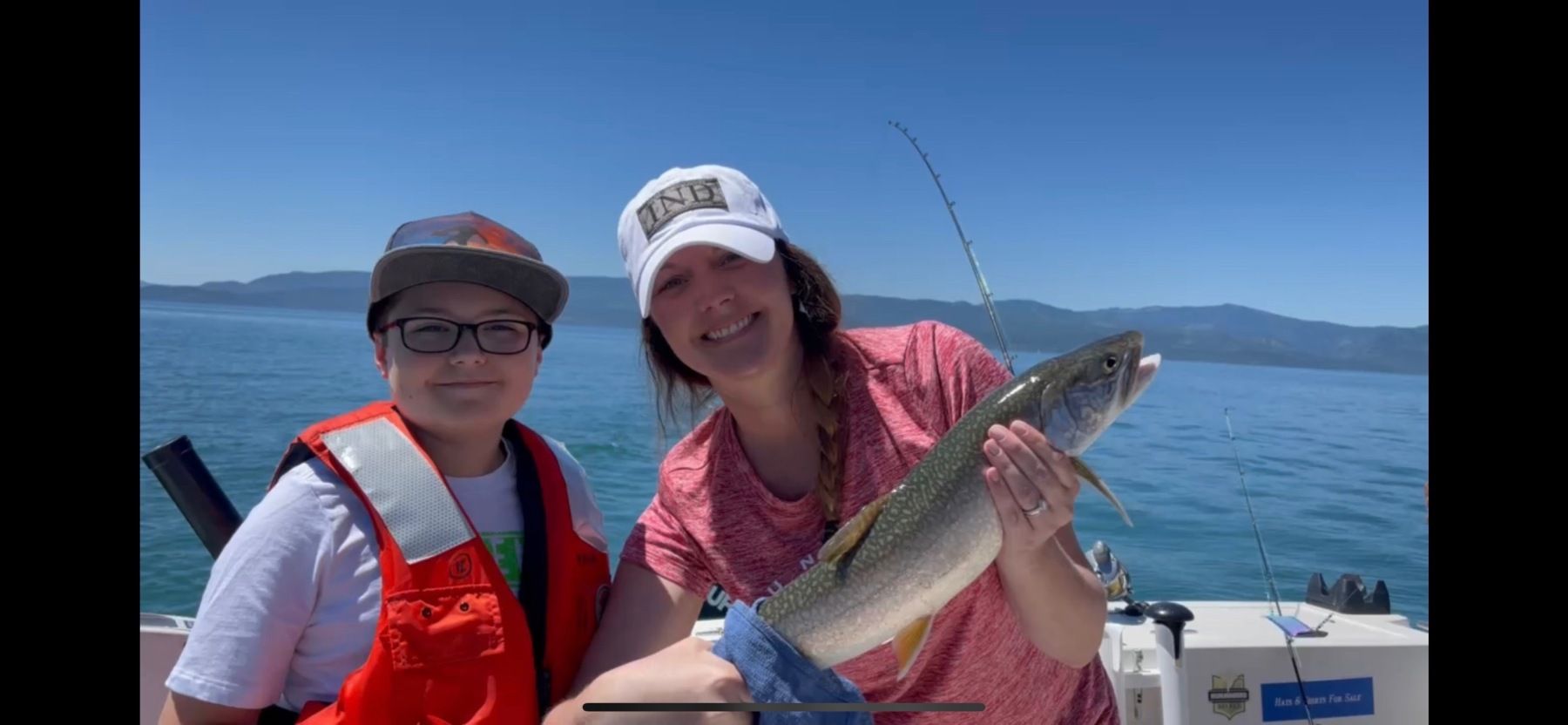 A woman and a boy are holding a fish on a boat.