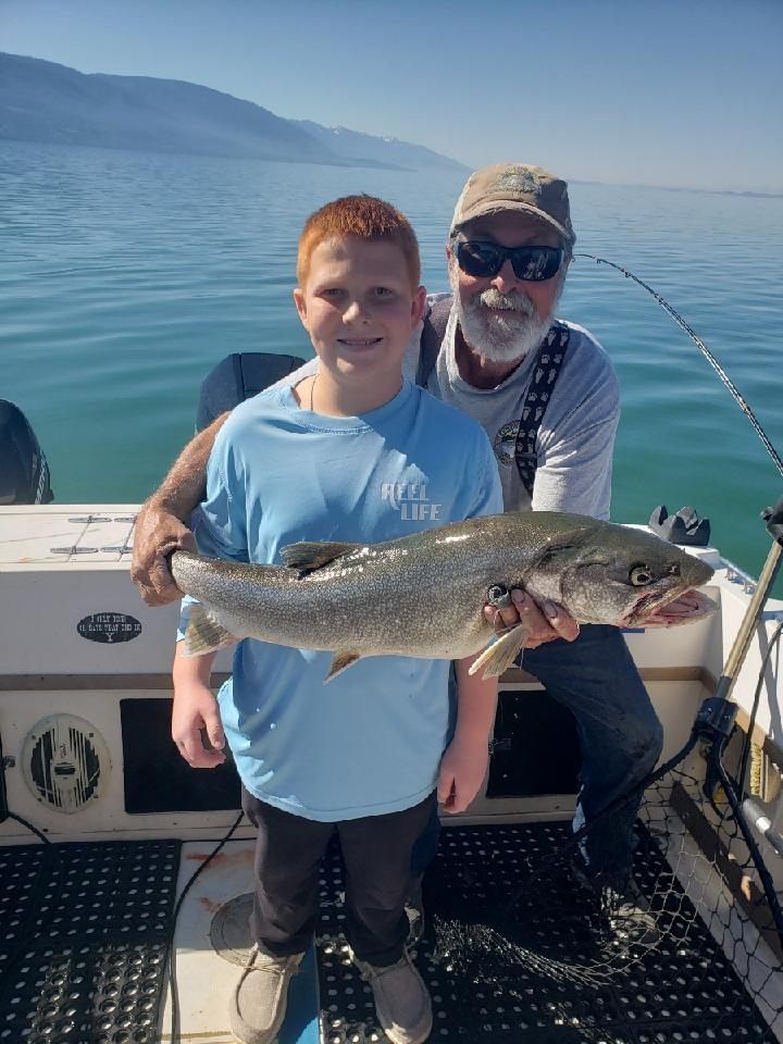 A man and a boy are holding a large fish on a boat.