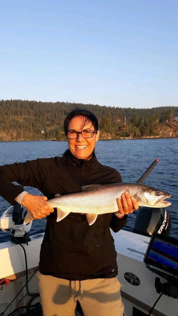 A woman is holding a large fish in her hands on a boat.