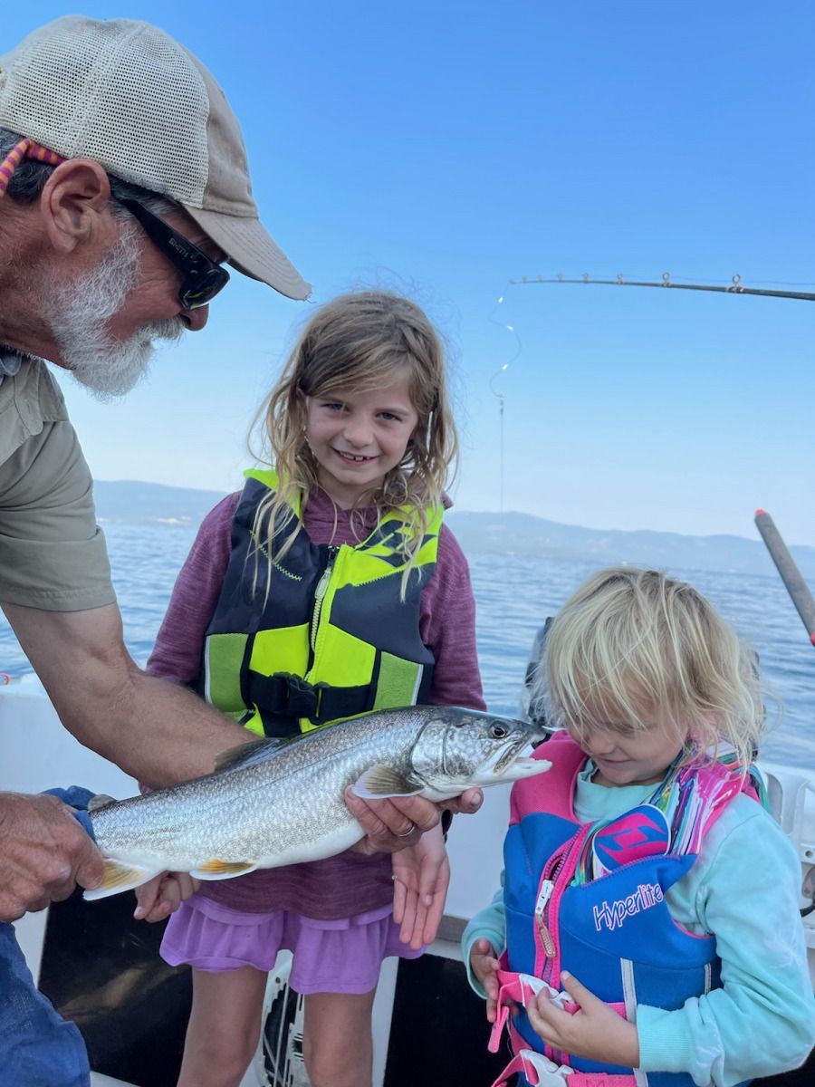 A man and two girls are holding a large fish on a boat.