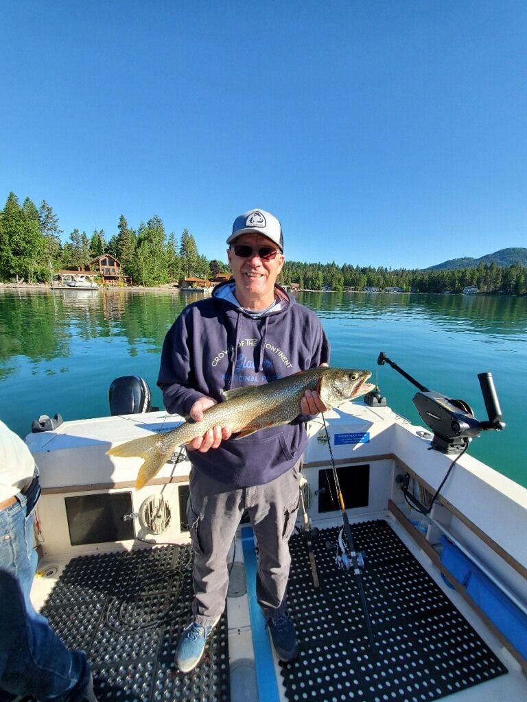A man is standing on a boat holding a large fish.