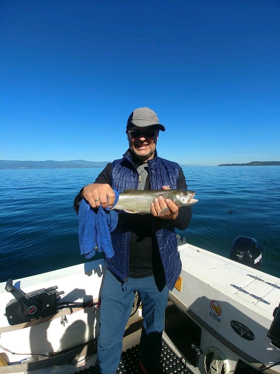 A man is holding a fish on a boat in the water.