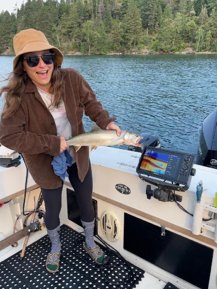 A woman is standing on a boat holding a fish.