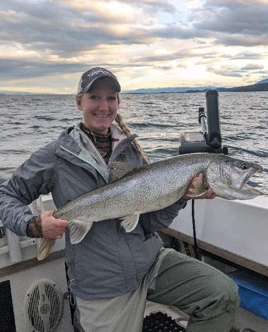 A woman is holding a large fish on a boat.