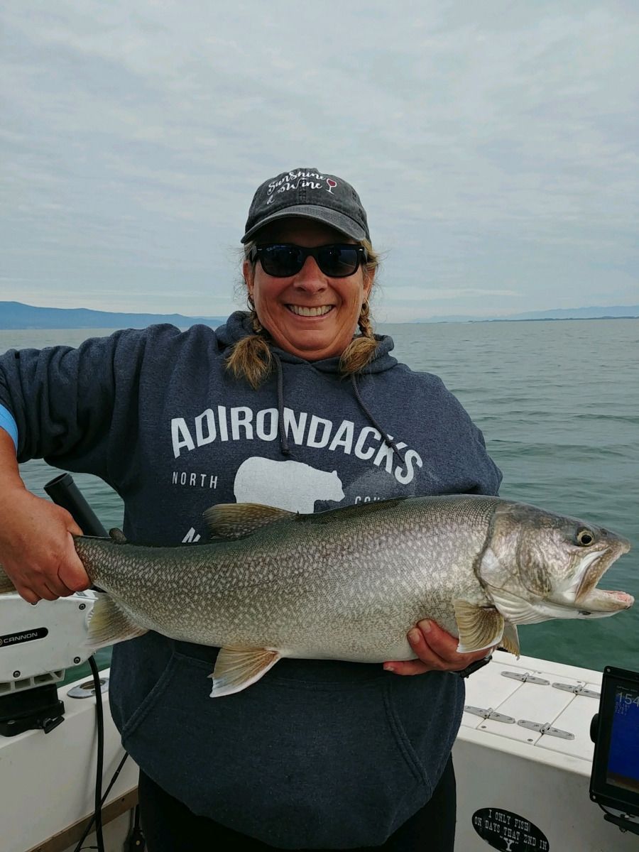 A woman is holding a large fish on a boat.