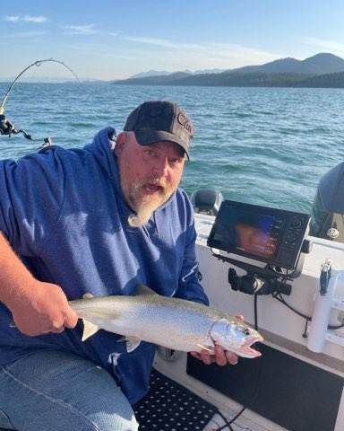 A man is sitting on a boat holding a fish.