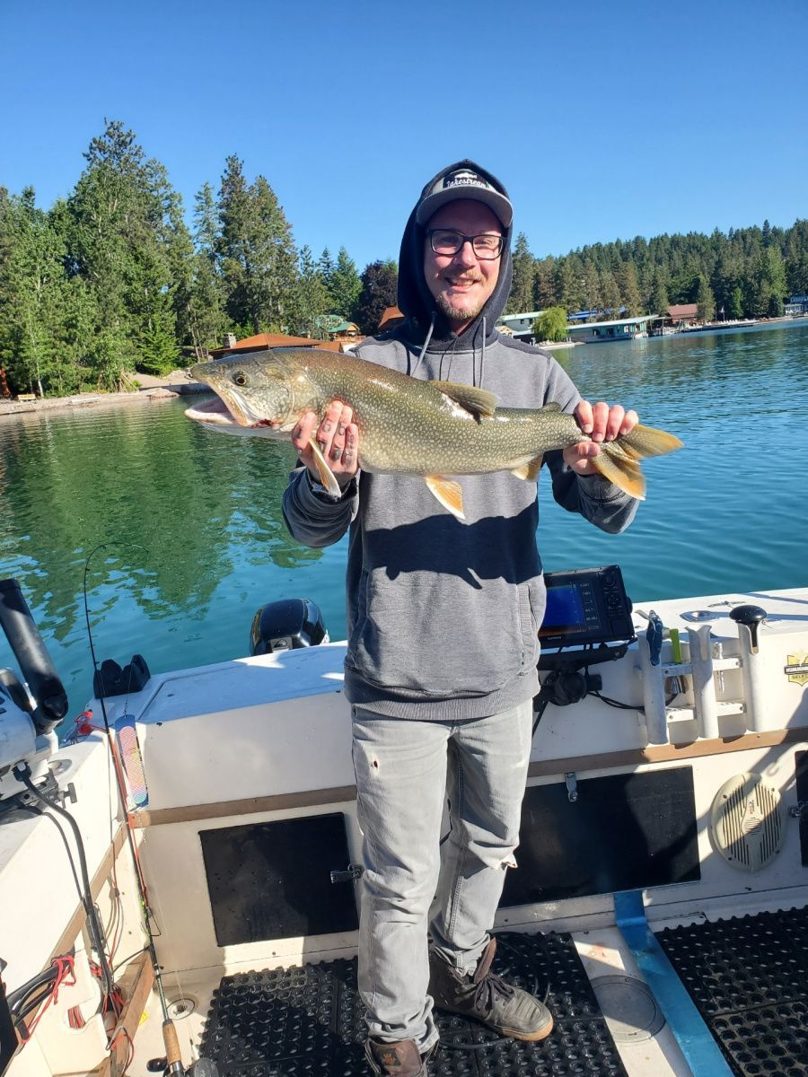 A man is standing on a boat holding a large fish.