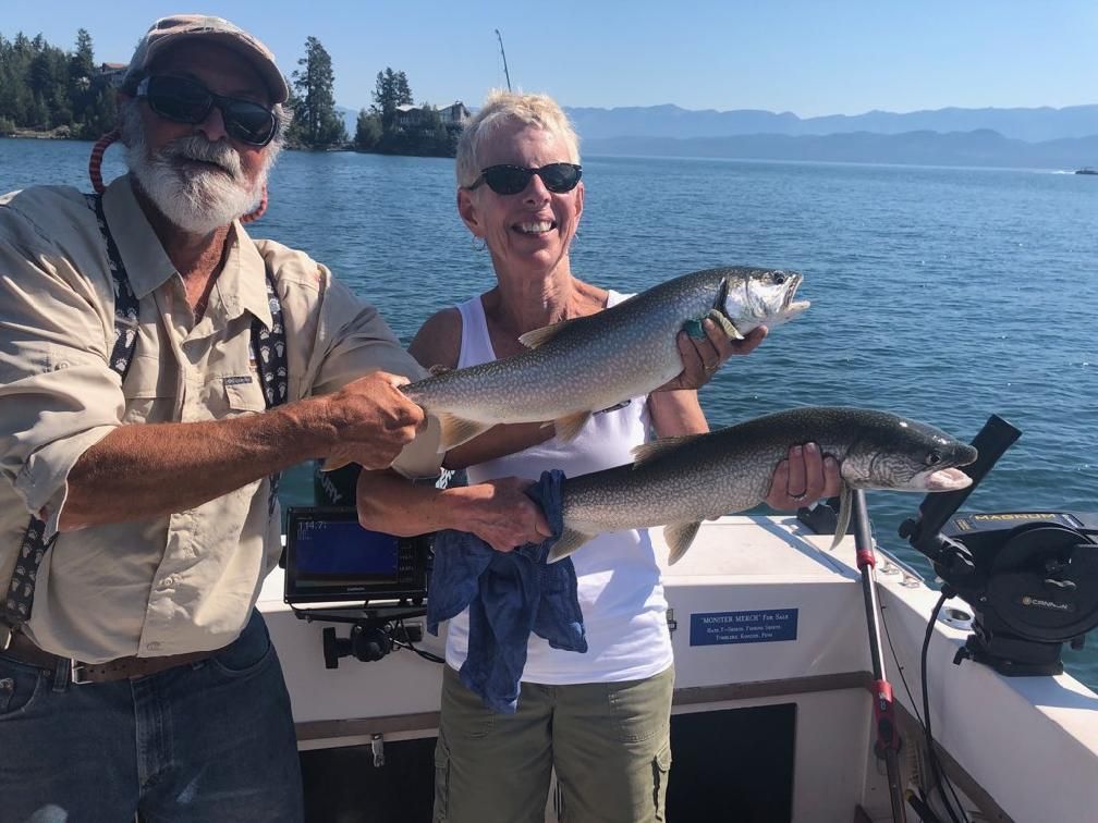A man and a woman are holding two fish on a boat.