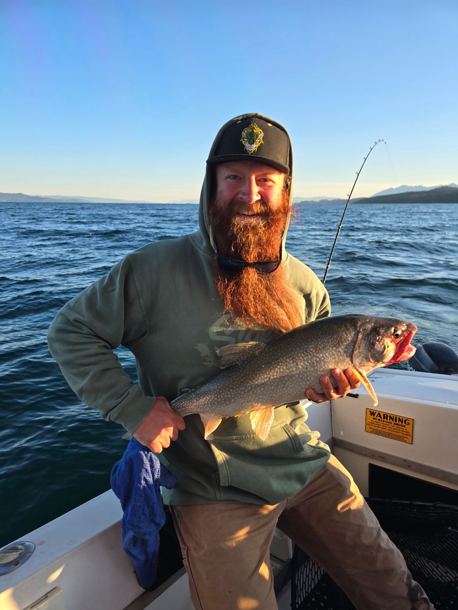 A man with a beard is holding a fish on a boat.