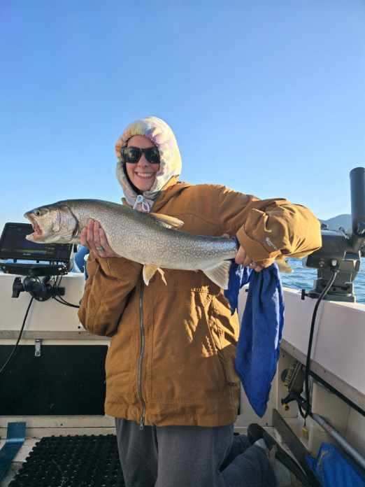 A woman is holding a large fish on a boat.