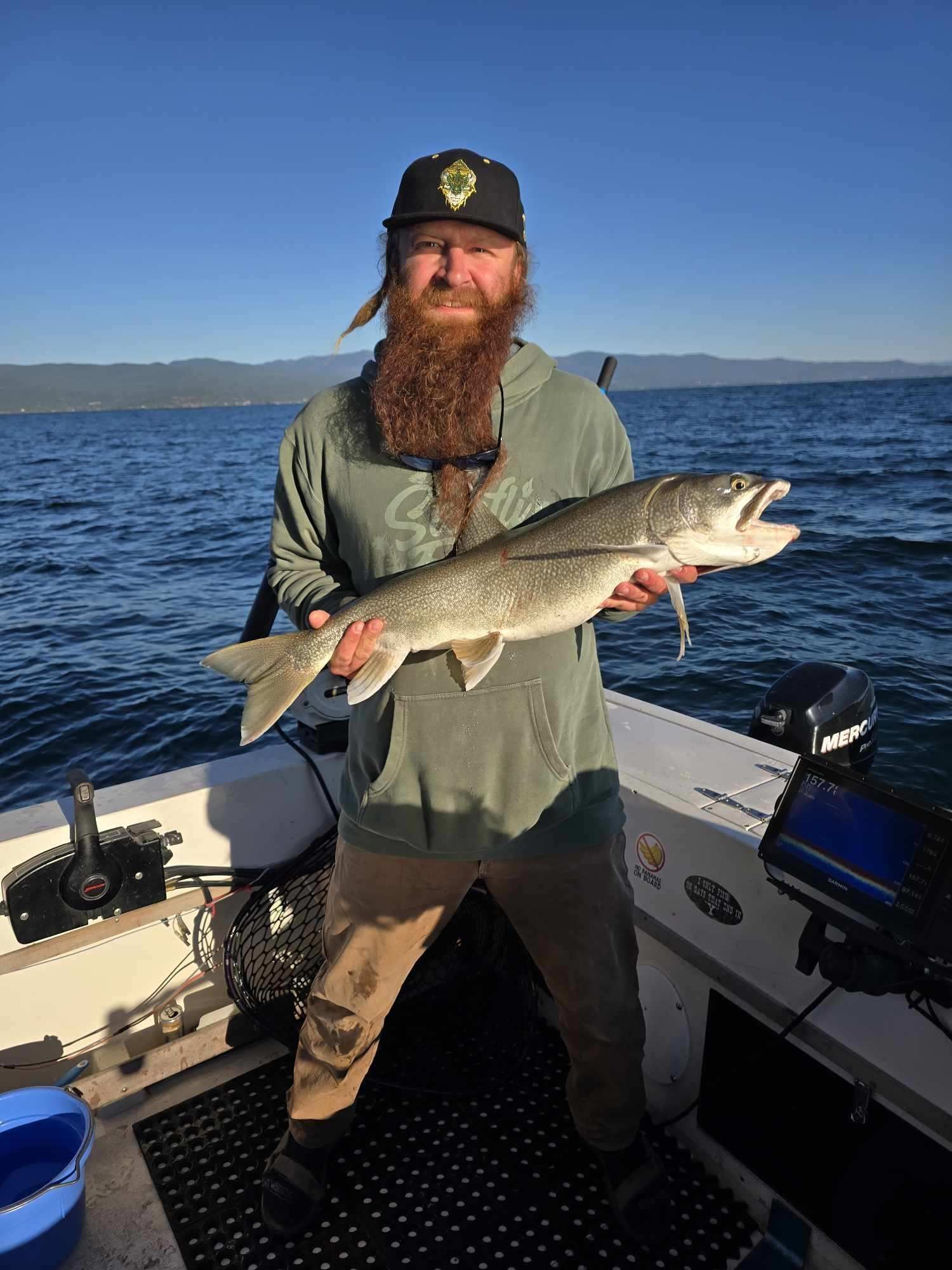A man with a beard is holding a large fish on a boat.