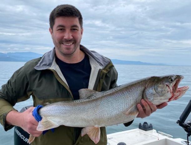 A man is holding a large fish on a boat.