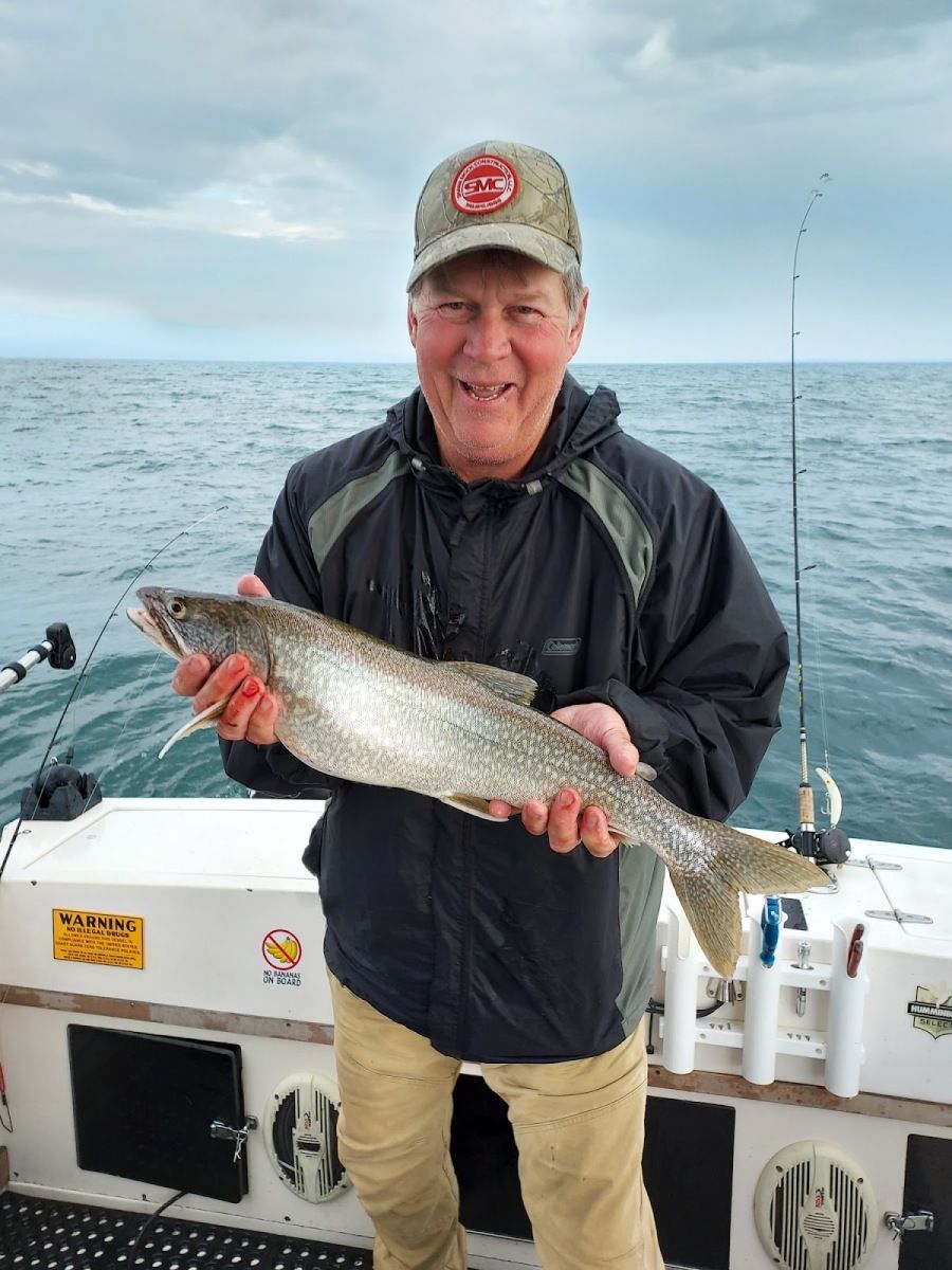 A man is holding a fish on a boat in the ocean.