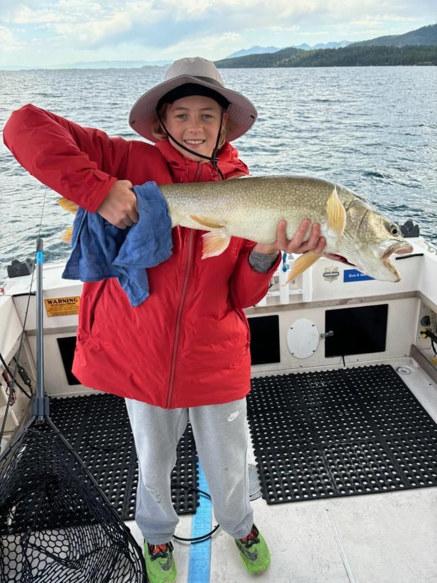 A young boy is holding a large fish on a boat