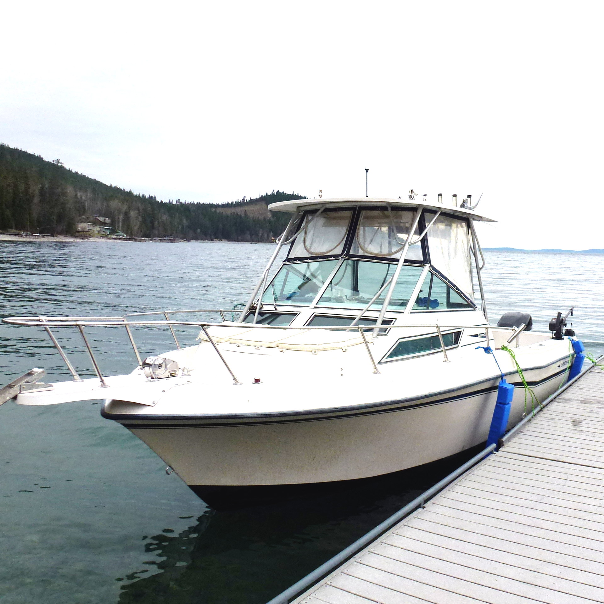 A white boat is docked at a dock in the water