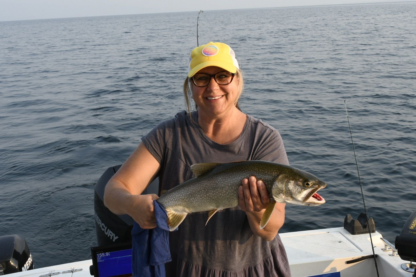 A woman is holding a fish on a boat in the ocean.