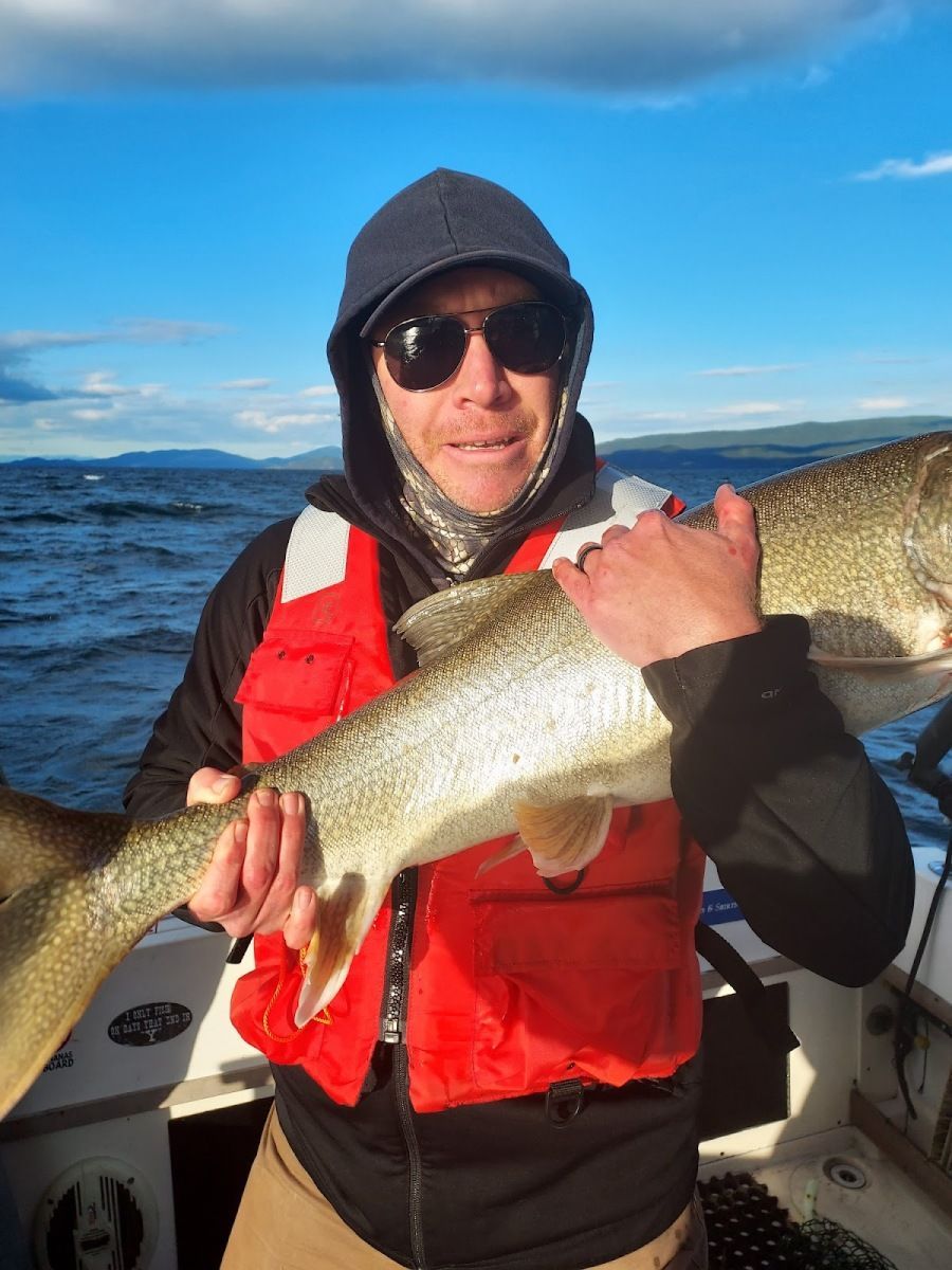 A man in a life vest is holding a large fish on a boat.
