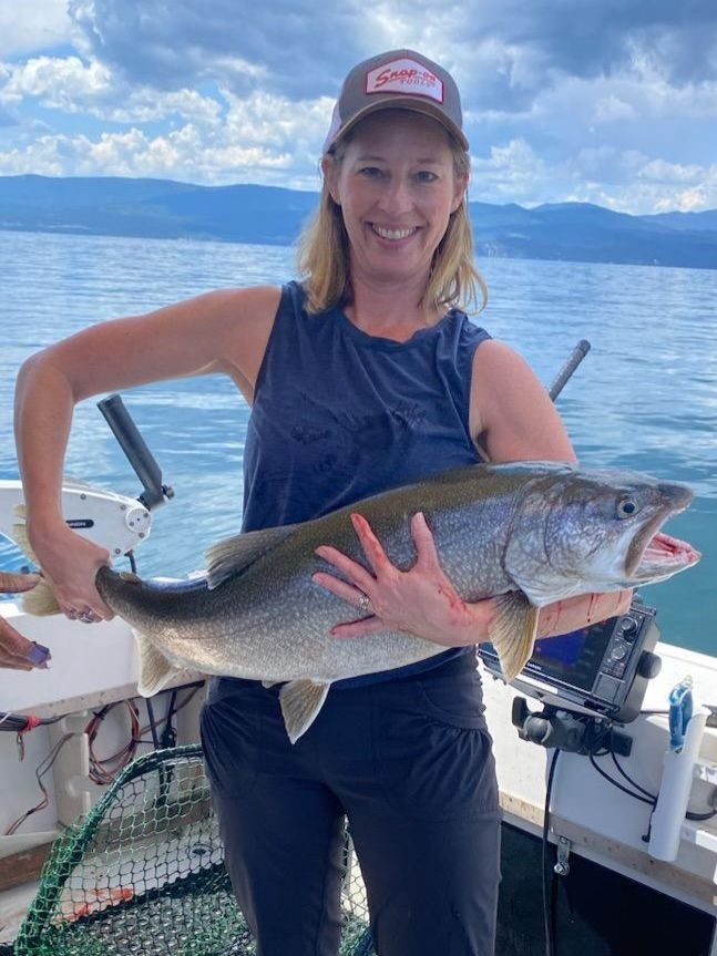 A woman is holding a large fish in her hands on a boat.