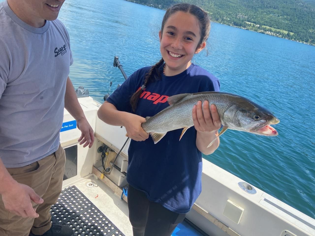 A young girl is holding a fish on a boat.