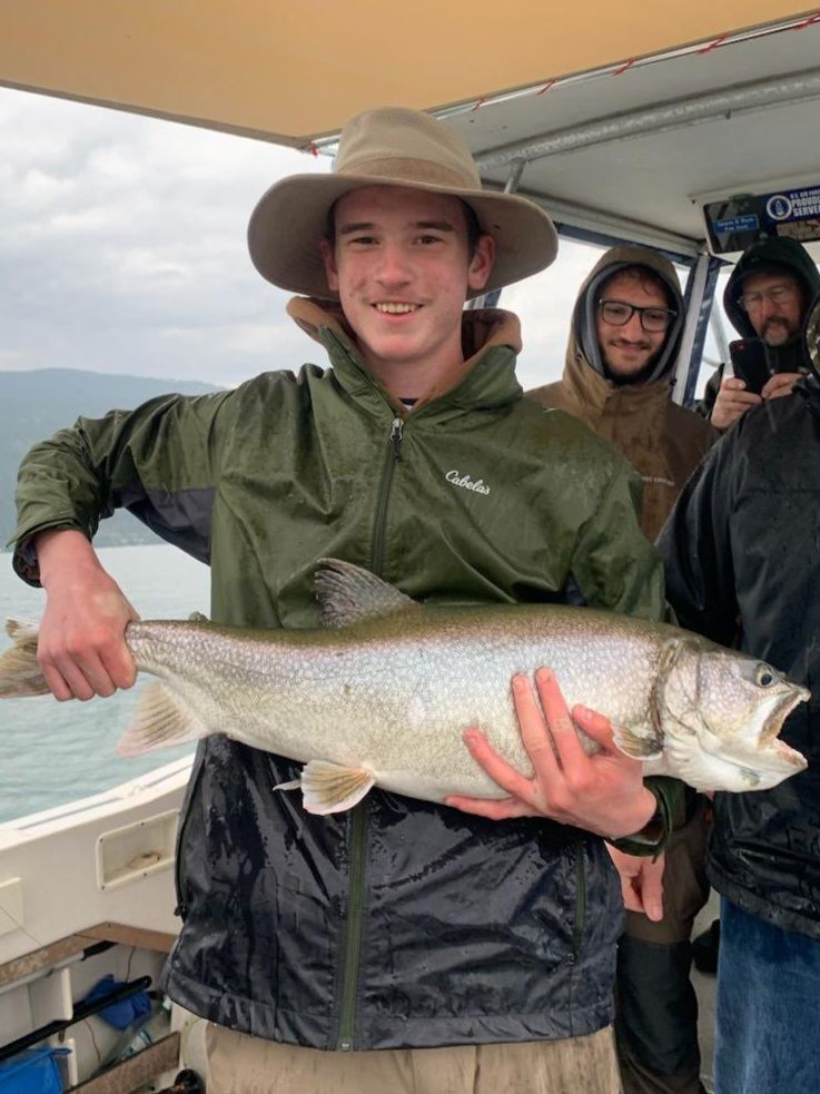 A young man is holding a large fish on a boat.