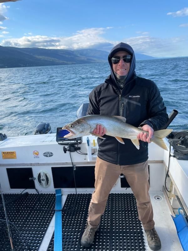 A man is standing on a boat holding a fish.