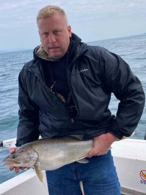 A man in a black jacket is holding a large fish