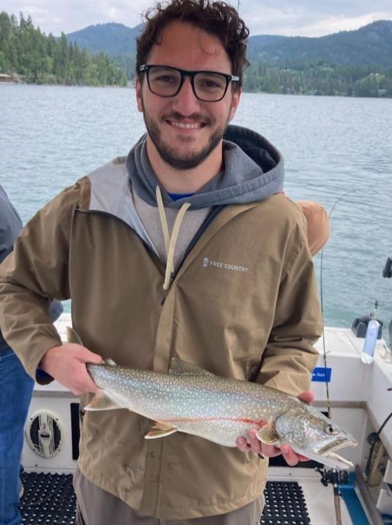 A man in a brown jacket is holding a fish