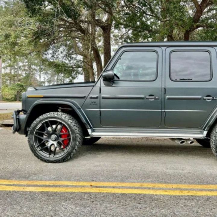 A black jeep with red brake calipers is parked on the side of the road.