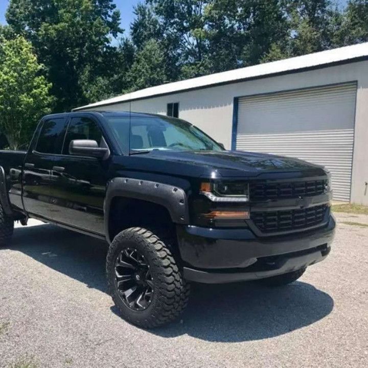 A black truck is parked in front of a garage.