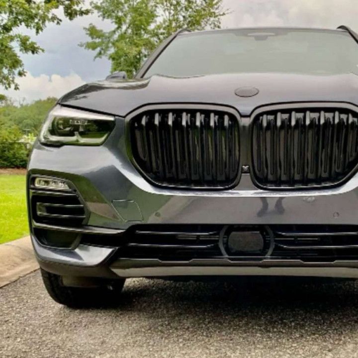 A bmw x5 is parked in a driveway with trees in the background.