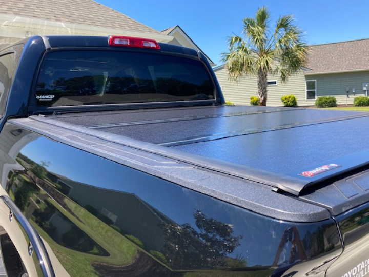 A black truck with a black bed cover is parked in front of a house.