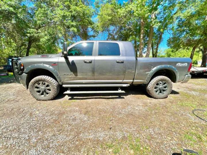 A gray ram truck is parked in a gravel lot.