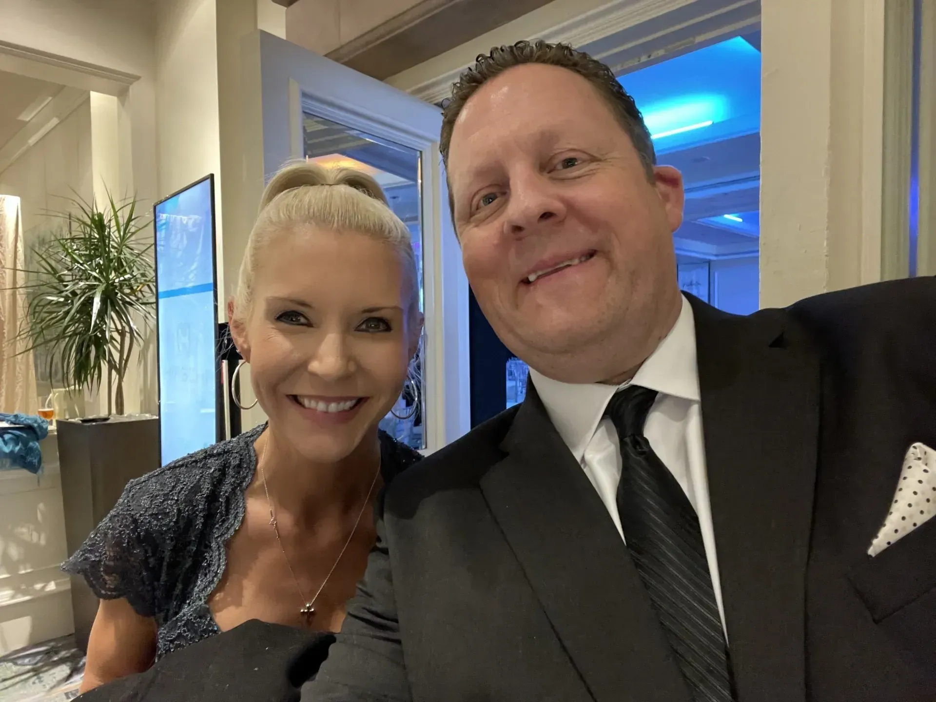 a man in a suit and tie is posing for a picture with a woman in a dress