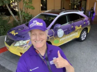 a man is giving a thumbs up in front of a car that says voice america