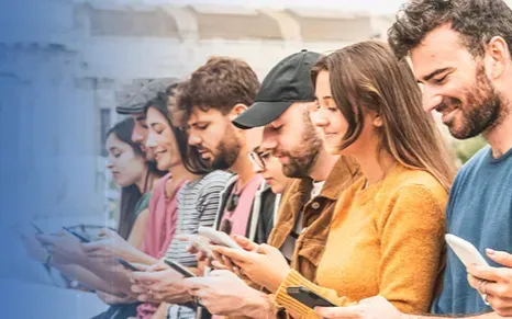 a group of people are standing in a row looking at their phones