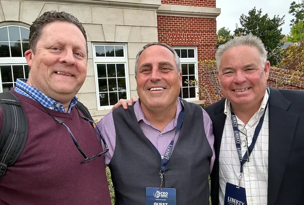 three men posing for a picture in front of a brick building