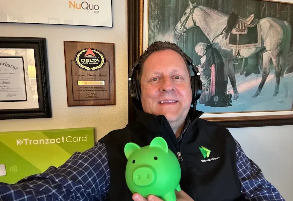 a man wearing headphones is holding a green piggy bank