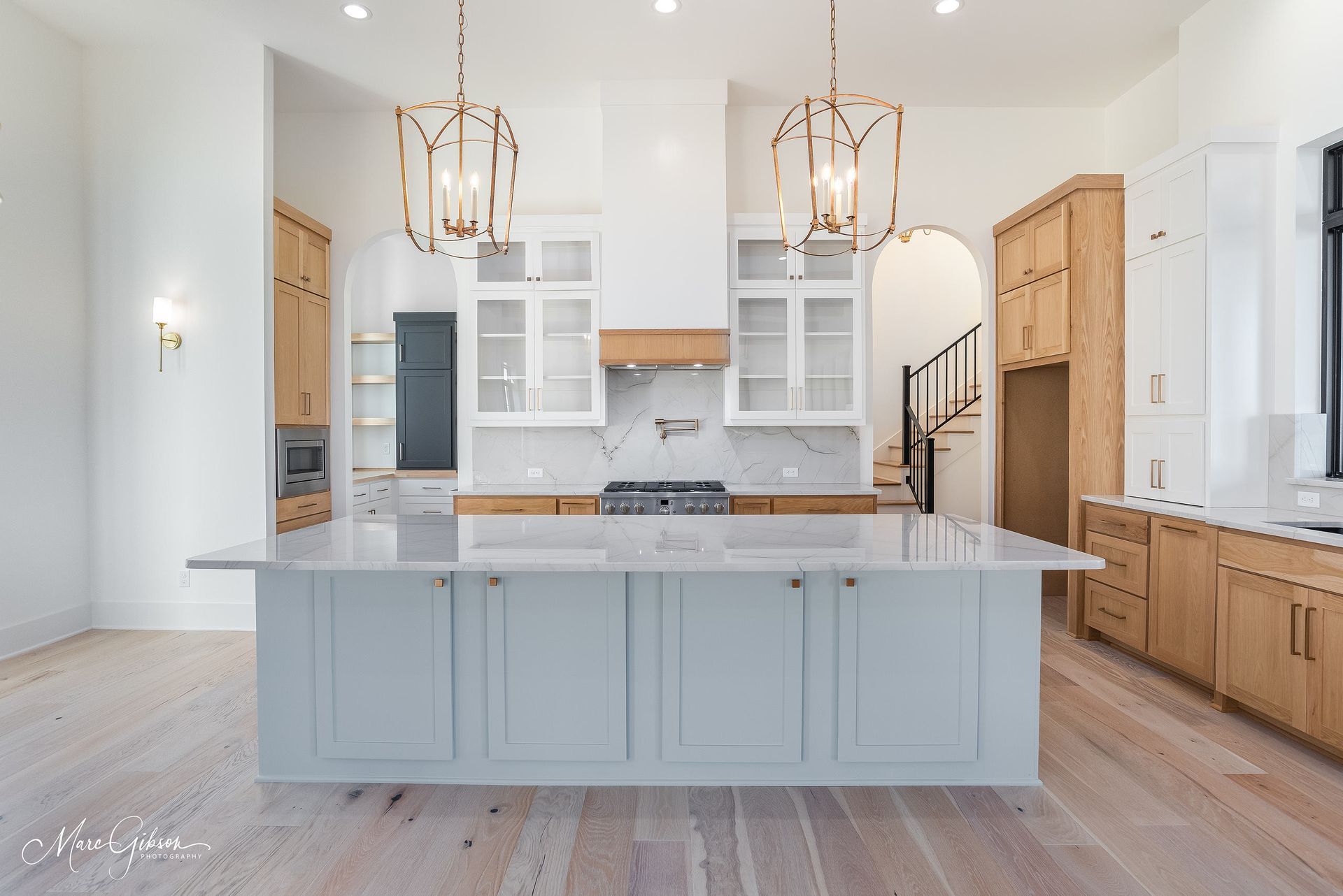 Spacious kitchen with large island, light blue cabinets, marble countertops, and wood accents.
