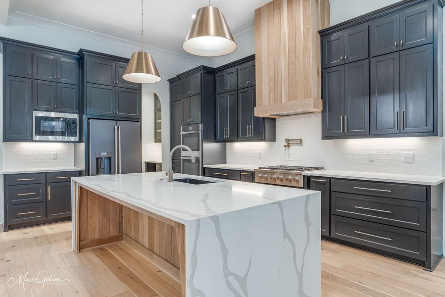 Modern kitchen with gray cabinets, white countertops, and wood accents.
