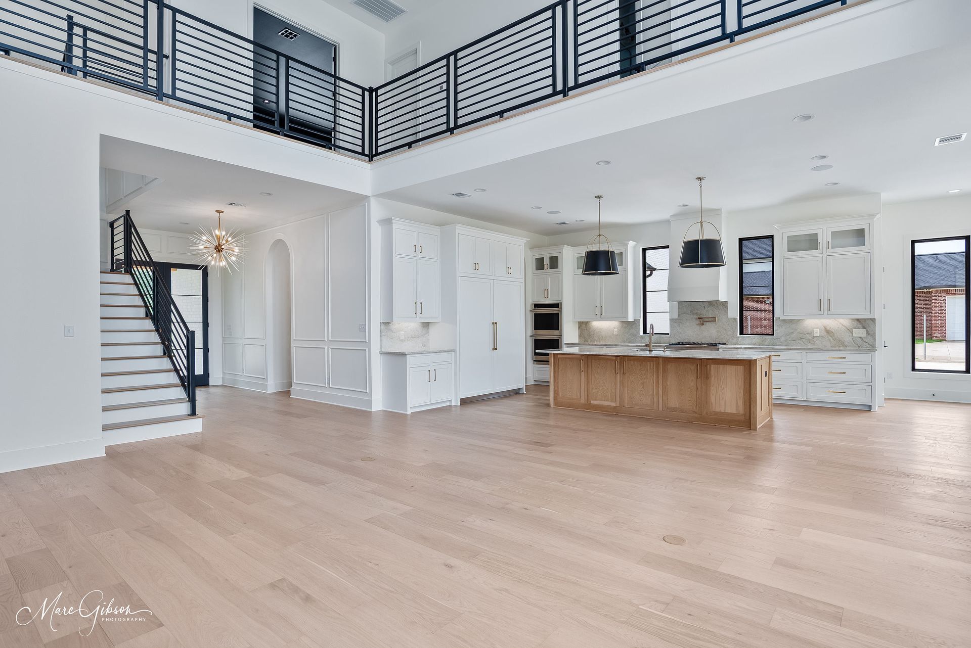 Spacious, bright kitchen and living area with a light wood floor, white cabinetry, and a balcony.